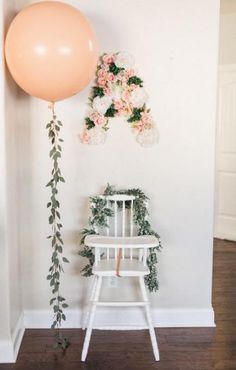 a white chair with flowers on it and a balloon hanging from the wall next to it