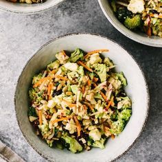 two bowls filled with broccoli, carrots and other vegetables on top of a table