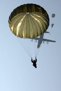 a man is parasailing in the sky with an airplane behind him and another person below