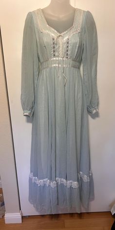 Amazing Vintage authentic Gunne Sax dress from the 70's!  Maxi length.  Long sleeve (sheer).  Zipper in back with attached tie.  Beautiful gauzy sky blue cotton/poly blend with a white nylon lining.  Beautiful lace accents with floral ribbon.  Lace up corset front.  In Excellent Vintage Condition with one small pen mark on bottom.  Size 9 on tag.  Measurements:  Bust: 32" Waist: 26" Length: 55" Shoulders: 24" Sleeve Length: 31.5" Purple Gunne Sax Dress, Gunne Sax Dress Pattern, Sax Dress, Gunne Sax Dress, Floral Corset, Floral Ribbon, Small Pen, Gunne Sax, Prairie Dress