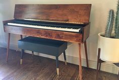 an old piano is sitting next to a potted cacti on the floor