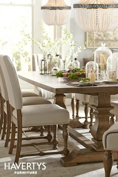 a dining room table with white chairs and chandelier