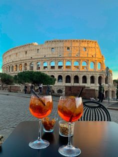 two glasses filled with drinks sitting on top of a table next to an old building