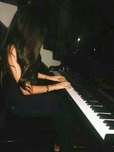 a woman sitting at a piano playing it