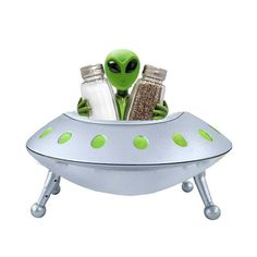 an alien sitting on top of a saucer with salt and pepper shakers in it