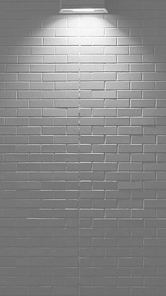 a black and white photo of a brick wall with a light on it's side