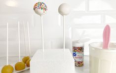 some cake pops are next to a container of sprinkles and an ice cream