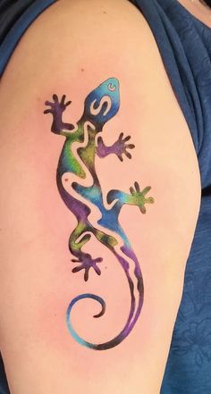 a colorful lizard tattoo on the back of a woman's left arm and shoulder