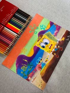 a drawing book with colored pencils next to it