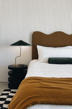 a bed sitting next to a nightstand with a lamp on it's side table