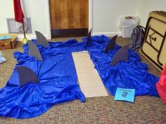 an image of a room setting with shark decorations on the floor and blue tarp covering it