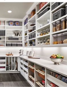 a kitchen with white cabinets and shelves filled with food