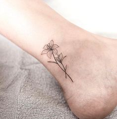 a small flower tattoo on the ankle that is sitting on a person's foot