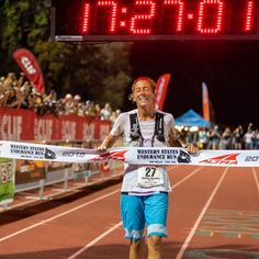 a man crosses the finish line in front of an electronic clock that reads 10 20