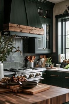 a kitchen with dark green cabinets and wooden counter tops, an island in the middle