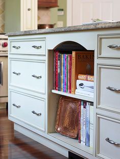 an open book shelf in the middle of a kitchen with many books on top of it