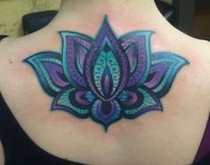 the back of a woman's neck with an intricate tattoo design on her shoulder