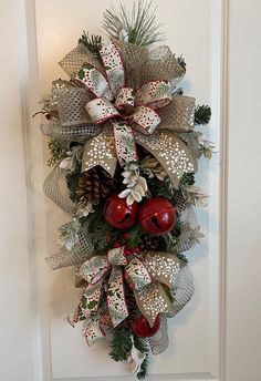 a christmas wreath hanging on the side of a door with bells and pine cones attached to it