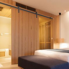 a bed sitting in a bedroom next to a wooden wall and closets with sliding doors