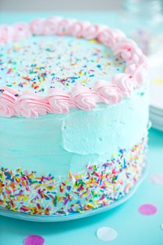 a frosted cake with sprinkles and pink icing on a table