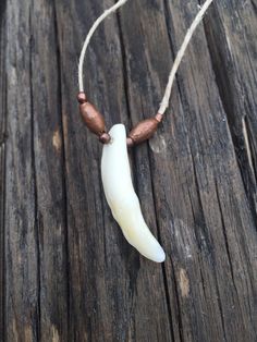 a white and brown beaded necklace with a banana on it's end sitting on a wooden surface