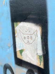 graffiti on the side of a wall with a cat's face drawn on it