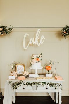 a cake table with flowers and greenery on it, along with other desserts