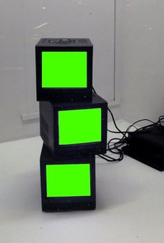 two black boxes with green squares on them are sitting next to a laptop and other electronic equipment