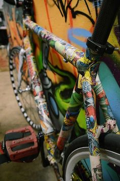 the bike is covered in colorful graffiti and has a black handlebar with red grips