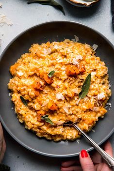 a bowl filled with oatmeal and garnished with fresh sage leaves