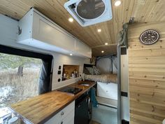 the interior of a camper with wood paneling and white appliances, including a stove top oven