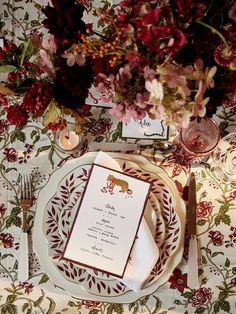 the table is set with red and white plates, silverware, and floral napkins