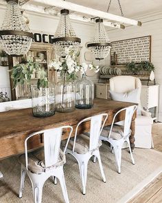 the dining room table is surrounded by white chairs and chandelier hanging from the ceiling