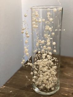 a glass filled with white flowers on top of a wooden table