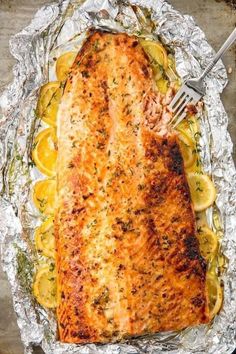 a piece of salmon on foil with lemons and herbs