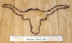 a wooden floor with a ruler on it and a cow's head made out of barbed wire