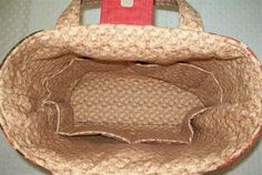 an open purse sitting on top of a white table next to a red and brown bag