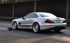 a silver mercedes slk driving down the road