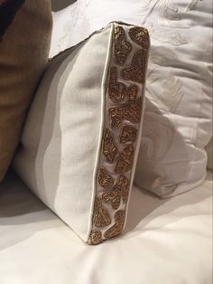 a white pillow sitting on top of a bed next to a brown pillow cover and pillows