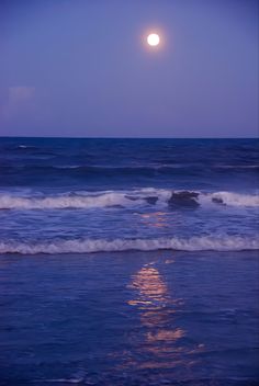 the moon shines brightly over the ocean as it reflects in the water's surface