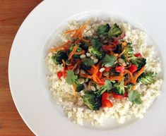 a white plate topped with rice and veggies on top of a wooden table