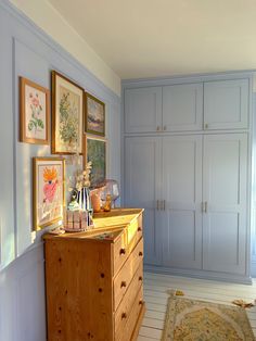 a room with blue walls and pictures on the wall, including an old dresser in the corner