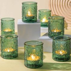 several green glass candles sitting on top of a table