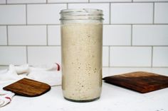 a glass jar filled with food sitting on top of a counter next to a cutting board