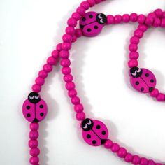 a pink beaded necklace with black and white ladybugs on it