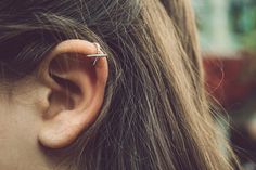 a woman with an ear piercing in the shape of a cross on her left ear