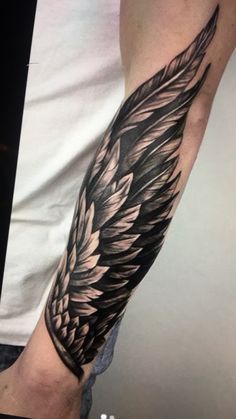 a man's arm with a black and white tattoo design on the left forearm