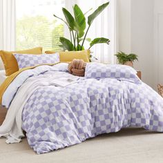 a bed covered in checkered comforter next to a potted plant