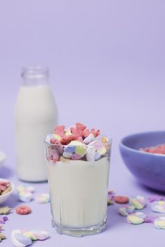 two glasses filled with marshmallows next to a bowl of cereal