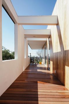 a long hallway with wooden floors and white walls, leading to the outside deck area